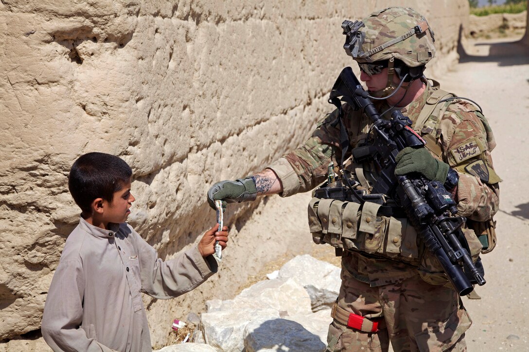 U.S. Army Staff Sgt. Brian Santos gives a young boy a present during a patrol in Sayghani village in Parwan province, Afghanistan, Sept. 27, 2014. Santos is assigned to the 454th Engineer Company Route Clearance.