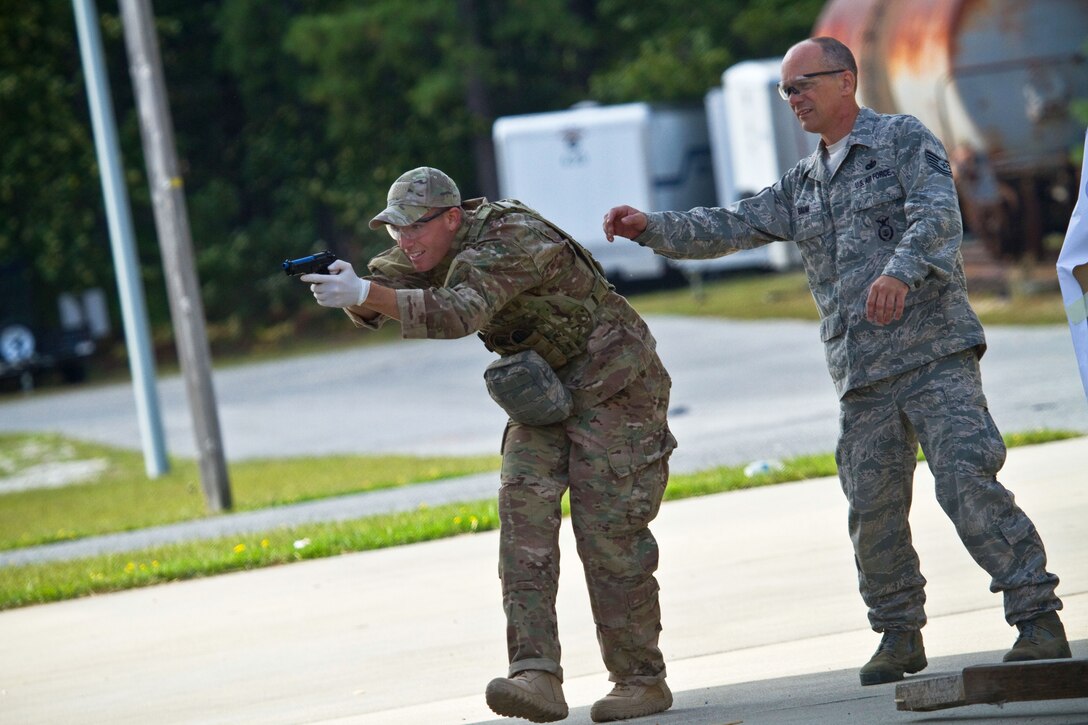 Air Force Tech. Sgt. Jack Baum, right, observes as Air Force Senior Airman Jake McGrattan fires simulation rounds at targets during tactical combat casualty care training on the Anthony Canale Training Center in Egg Harbor Township, N.J., Sept. 19, 2014. Baum and McGrattan are assigned to the New Jersey National Guard's 177th Security Forces Squadron.
