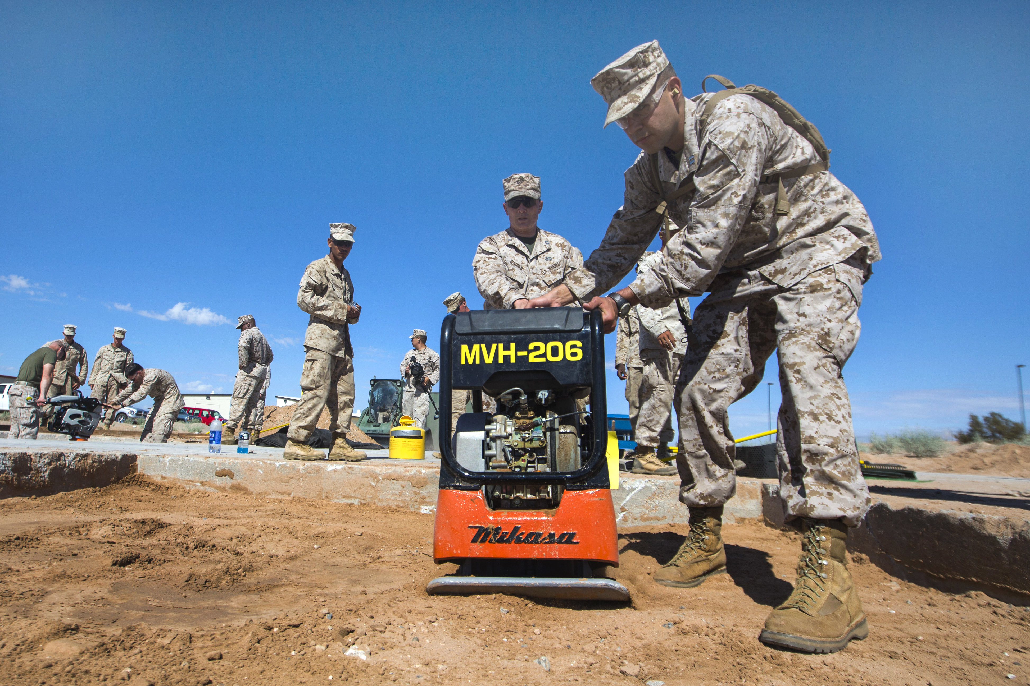 Marine Corps aviation ground support students use a plate compactor to
