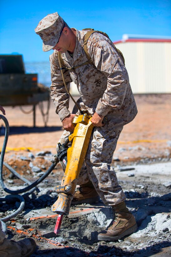 Marine Corps Capt. George Ivascu utilizes a 90-pound air-powered jack hammer to crumble cement during an airfield damage repair practical application on Canon Air Defense Complex near Yuma, Ariz., Sept. 20, 2014. Ivascu is assigned to Marine Wing Support Squadron 171, Marine Aircraft Group 12, 1st Marine Aircraft Wing.