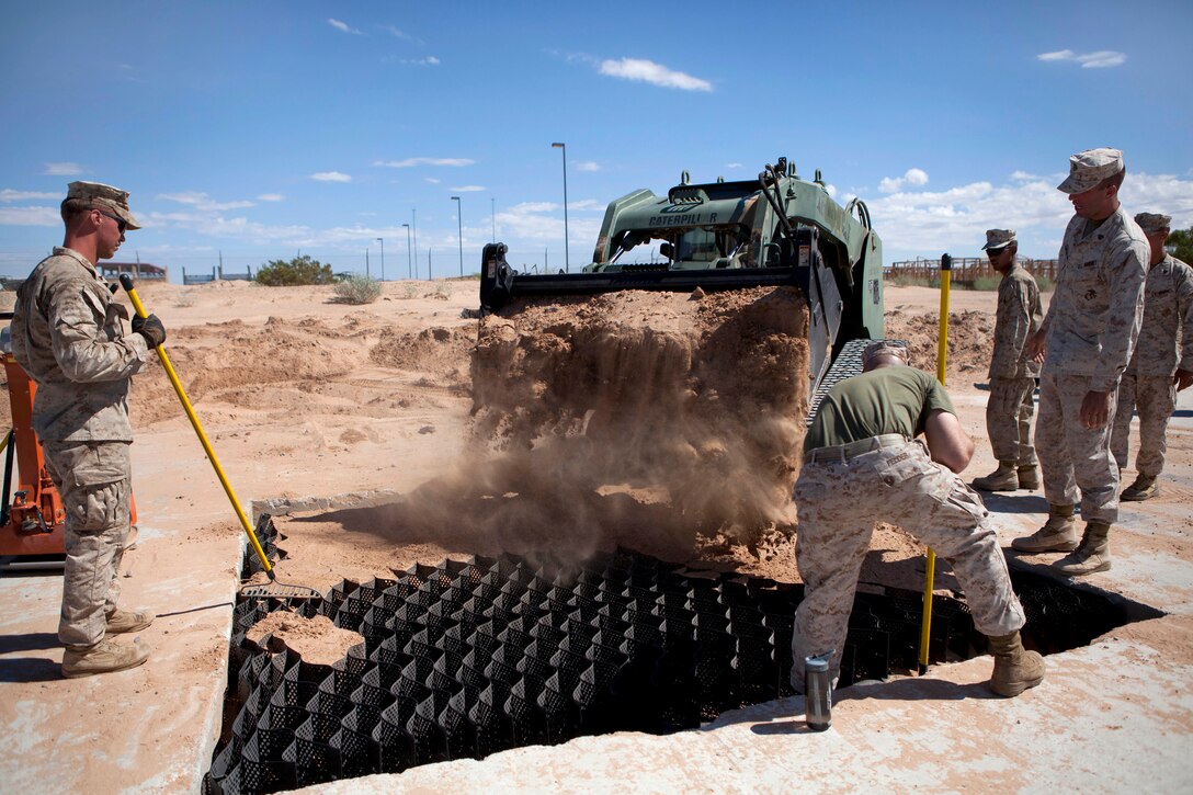 Marine Corps Aviation Ground Support students fill a crater with dirt during an airfield damage repair practical application on Canon Air Defense Complex near Yuma, Ariz., Sept. 20, 2014.