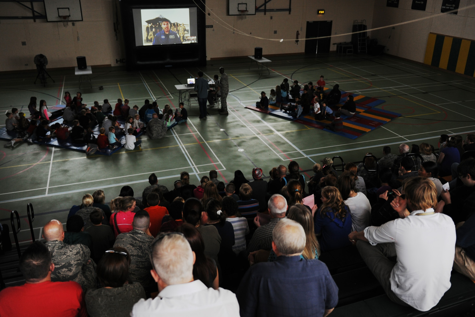 Students, parents and teachers listen as Air Force Col. Michael Hopkins describes the process he went through to become a NASA astronaut during a video teleconference inside the school gymnasium at RAF Alconbury, United Kingdom, Sept. 23, 2014. Hopkins said one of the most memorable experiences he had during his time aboard the International Space Station was when he viewed Earth during a spacewalk. (U.S. Air Force photo by Staff Sgt. Jarad A. Denton)