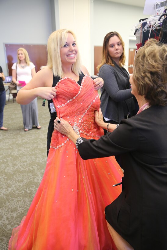 Samara Macias smiles as Jean Bender size matches a gown during Operation Ball Gown 2014 at Marine Corps Air Station Cherry Point, N.C., Sept. 26, 2014. The sixth annual event benefitted 300 military wives who received free ball gowns in preparation for the upcoming Marine Corps Birthday Ball. Macias is a Marine Aviation Logistics Squadron 14 spouse who will be attending the ball this November. Bender is a Mary Kay beauty consultant.