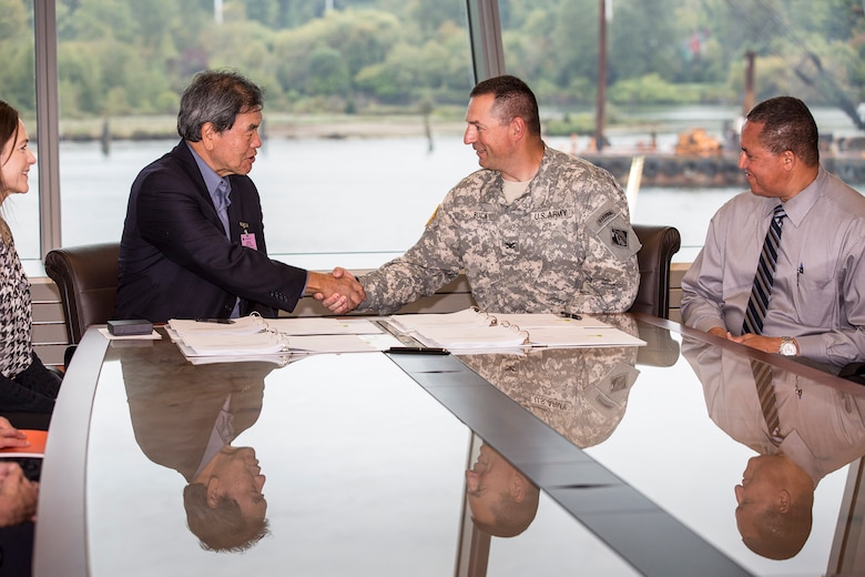 Port of Seattle Chief Executive Officer Tay Yoshitani and Seattle District Commander Col. John Buck shake hands before signing and entering into a $3 million cost-sharing  agreement at the U.S. Army Corps of Engineers district office here Sept. 29. The agreement is for a cost-shared feasibility study to investigate potential Port deepening alternatives and will determine if there is an economically-justifiable alternative to deepen Seattle Harbor’s East and West Waterways. Also pictured are, far left, Port of Seattle Seaport Managing Director Linda Styrk and, far right, Seattle District Deputy District Engineer for Programs & Project Management and Chief, Programs & Project Management Division Olton Swanson.