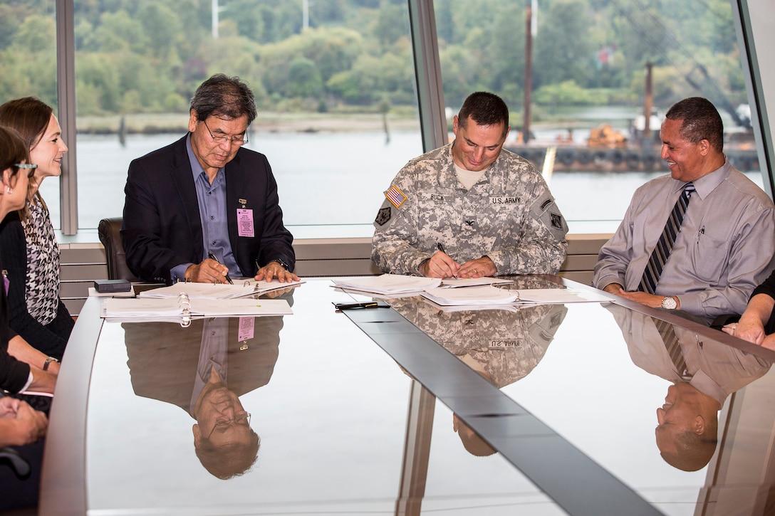 Port of Seattle Chief Executive Officer Tay Yoshitani and Seattle District Commander Col. John Buck sign and enter into a $3 million cost-sharing  agreement at the U.S. Army Corps of Engineers district office here Sept. 29. The agreement is for a cost-shared feasibility study to investigate potential Port deepening alternatives and will determine if there is an economically-justifiable alternative to deepen Seattle Harbor’s East and West Waterways. Also pictured are, far left, Port of Seattle Seaport Managing Director Linda Styrk and, far right, Seattle District Deputy District Engineer for Programs & Project Management and Chief, Programs & Project Management Division Olton Swanson. 