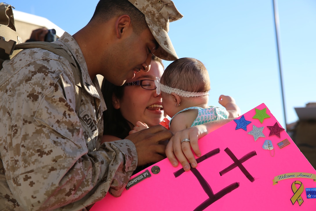 Lance Cpl. Brian Gonzales, field wireman, 1st Tank Battalion meets his daughter for the first time during the 1st Tank Battalion homecoming on the battalion’s tank ramp, Sept. 25, 2014. The battalion was deployed for seven months.