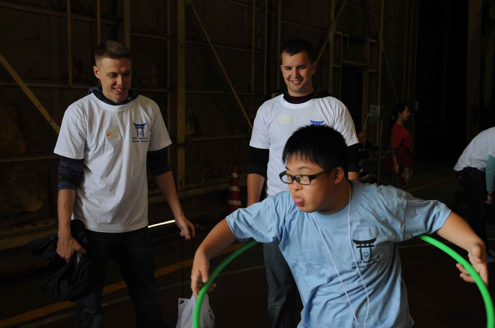 U.S. Air Force Senior Airman Auguste Archer, 35th Communications Squadron emergency security manager, and Senior Airman Jake Bruggenthies, 373rd Support Squadron client systems technician, observe a Special Olympics athlete hula hoop during the 28th Annual Special Olympics at Misawa Air Base, Japan, Sept. 27, 2014. Misawa Air Base personnel volunteered to be sponsors for the athletes and led them through sporting events. (U.S. Air Force photo by Airman Jordyn Rucker)