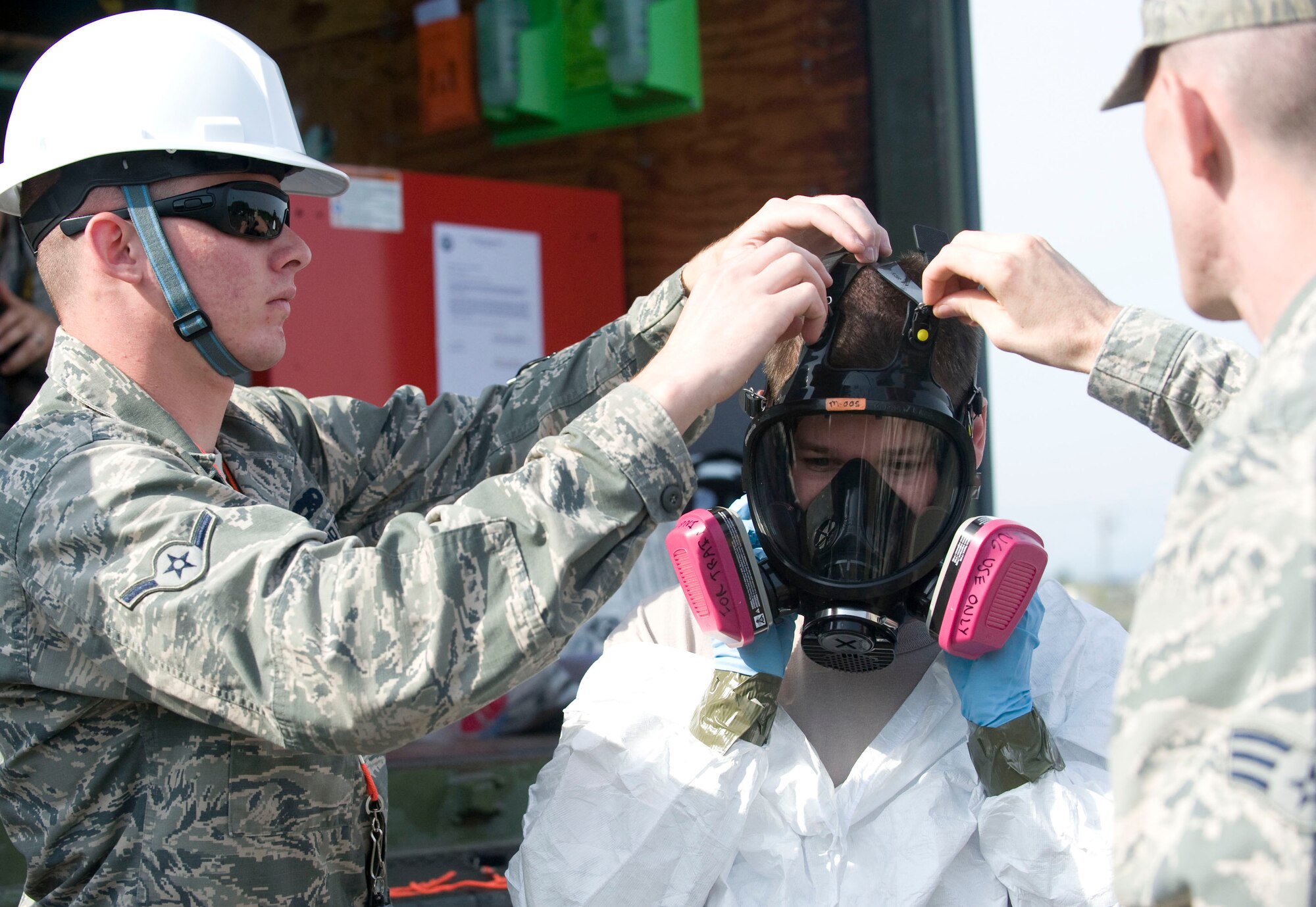 35th Maintenance Squadron crash recovery team members assist U.S Air Force Staff Sgt. Timothy Amburn in tightening his mask during a crash recovery exercise at Misawa Air Base, Japan, Sept. 23, 2014. During the exercise, team members ensured all personal protective equipment was properly worn to safely complete their mission. (U.S. Air Force photo by Staff Sgt. Alyssa C. Wallace)
