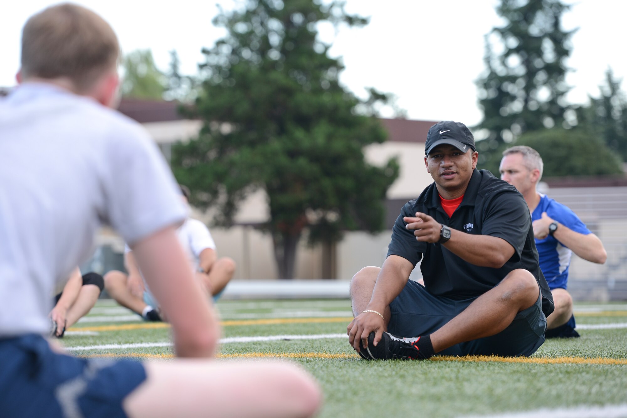 Tech. Sgt. Christian Martinez, Warrior Run Program coach, jokes with a participant while stretching at a workout session at Yokota Air Base, Japan, Sept. 19, 2014. Martinez is one of four coaches for the WRP, a program that assists community members in improving their overall health and wellness. (U.S. Air Force photo by Staff Sgt. Cody H. Ramirez/Released)