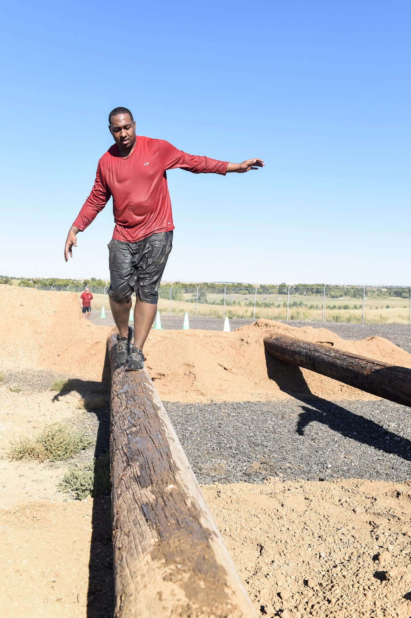 A Team Buckley member makes his way across a wooden beam during WARFIT Sept. 25, 2014, on Buckley Air Force Base, Colo. The 460th Civil Engineer Squadron hosted the September WARFIT, which consisted of a 5K run and a mud obstacle course. WARFIT is a way for the 460th Space Wing and base partner units to get together and stay physically fit. (U.S. Air Force photo by Senior Airman Phillip Houk/Released)