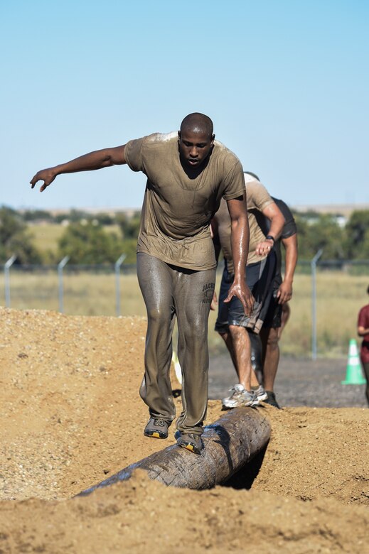 Senior Airman Waddell Howard and other Team Buckley members balance their way across a wooden beam as part of the WARFIT challenge Sept. 25, 2014, on Buckley Air Force Base, Colo. The 460th Civil Engineer Squadron hosted the September WARFIT, which consisted of a 5K run and a mud obstacle course. WARFIT is a way for the 460th Space Wing and base partner units to get together and stay physically fit. (U.S. Air Force photo by Senior Airman Phillip Houk/Released)