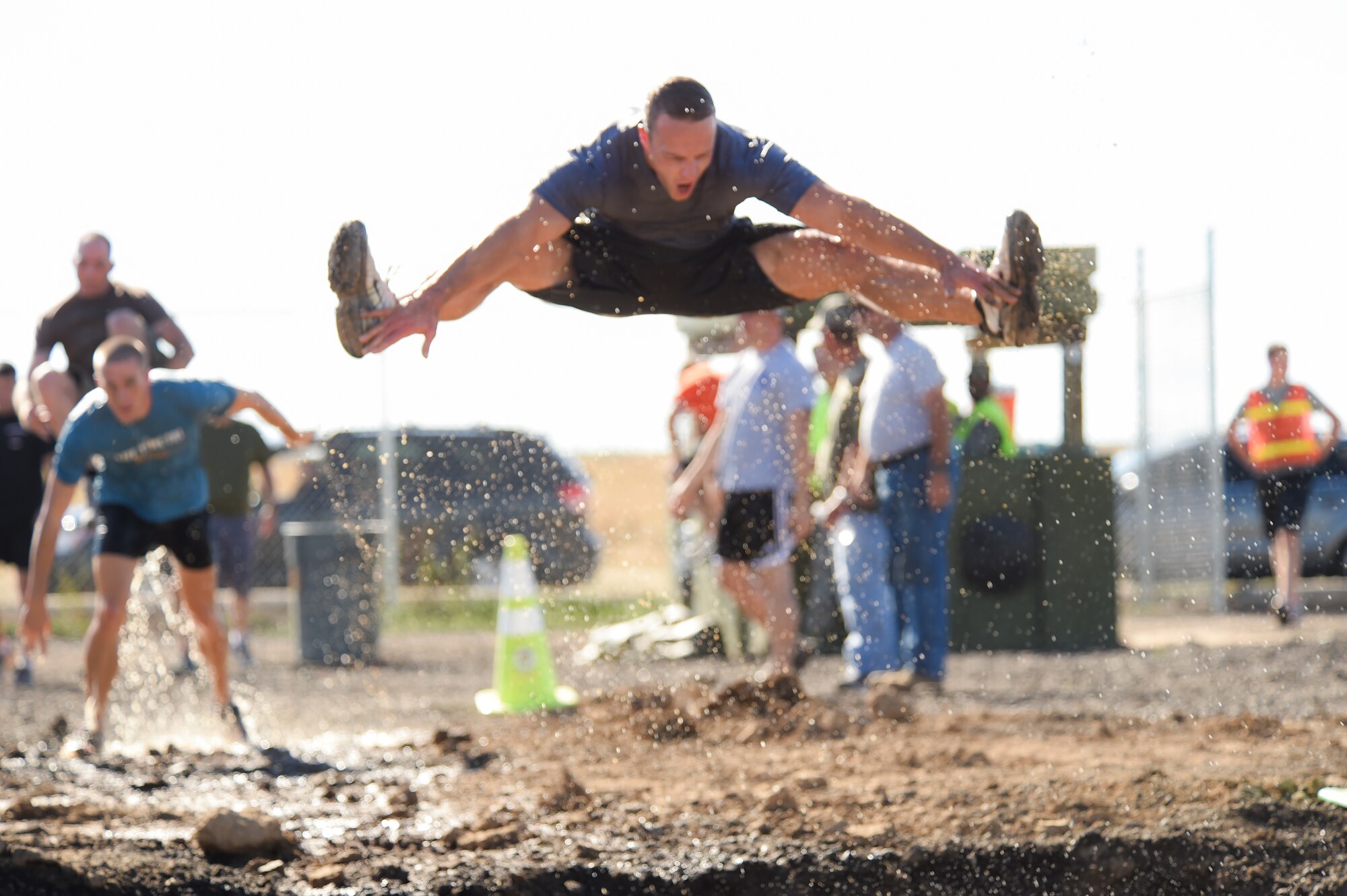 Capt. Luke McPherson jumps into a mud pit during WARFIT Sept. 25, 2014, on Buckley Air Force Base, Colo. The 460th Civil Engineer Squadron hosted the September WARFIT, which consisted of a 5K run and a mud obstacle course. WARFIT is a way for the 460th Space Wing and base partner units to get together and stay physically fit. (U.S. Air Force photo by Senior Airman Phillip Houk/Released)