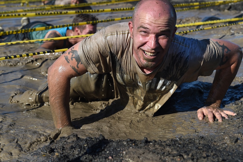 A Team Buckley member emerges from the mud after the low-crawl obstacle during WARFIT Sept. 25, 2014, on Buckley Air Force Base, Colo. The 460th Civil Engineer Squadron hosted the September WARFIT, which consisted of a 5K run and a mud obstacle course. WARFIT is a way for the 460th Space Wing and base partner units to get together and stay physically fit. (U.S. Air Force photo by Airman Emily E. Amyotte/Released)