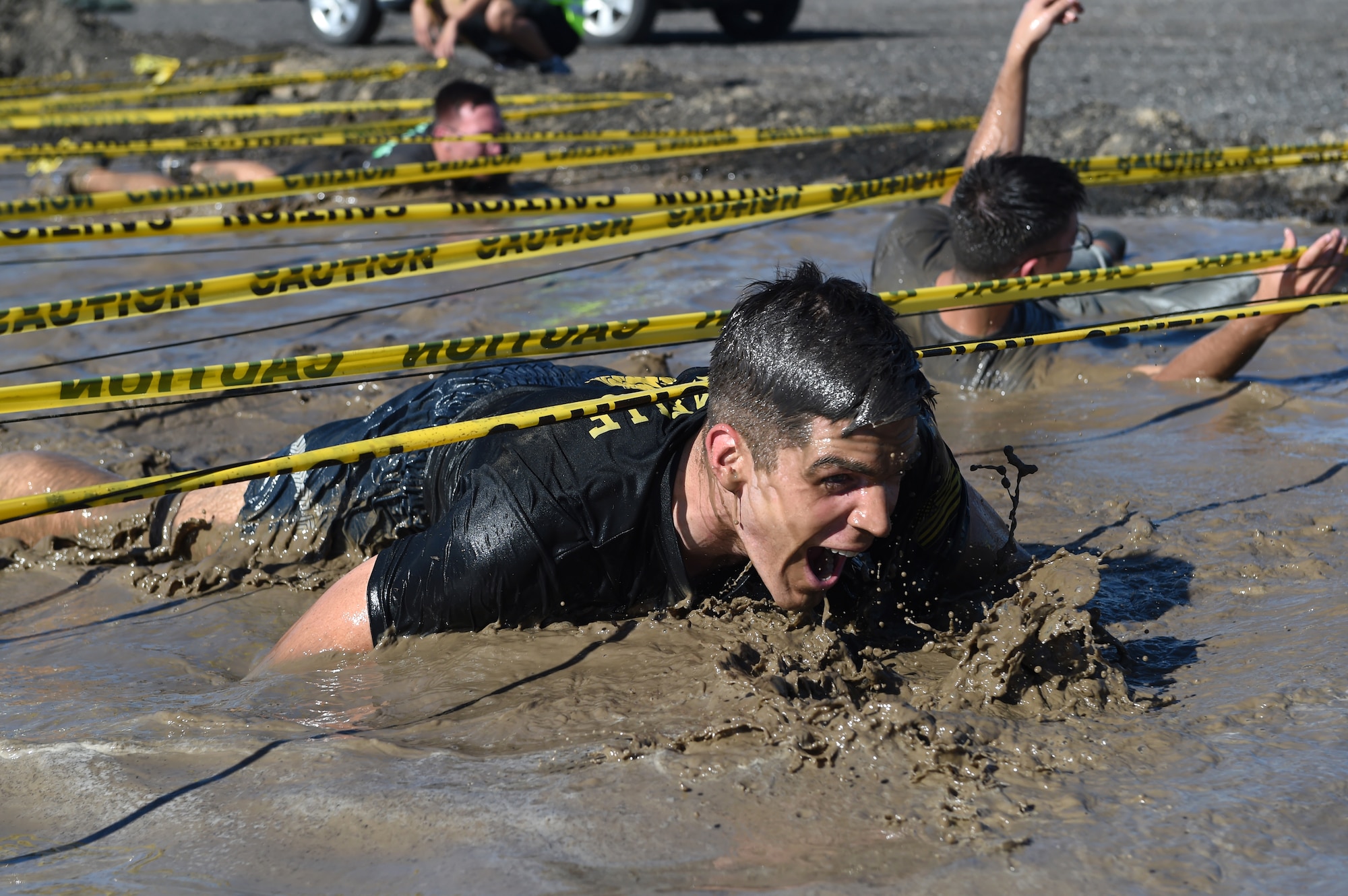 Team Buckley members traverses the low-crawl obstacle during WARFIT Sept. 25, 2014, on Buckley Air Force Base, Colo. The 460th Civil Engineer Squadron hosted the September WARFIT, which consisted of a 5K run and a mud obstacle course. WARFIT is a way for the 460th Space Wing and base partner units to get together and stay physically fit. (U.S. Air Force photo by Airman Emily E. Amyotte/Released)