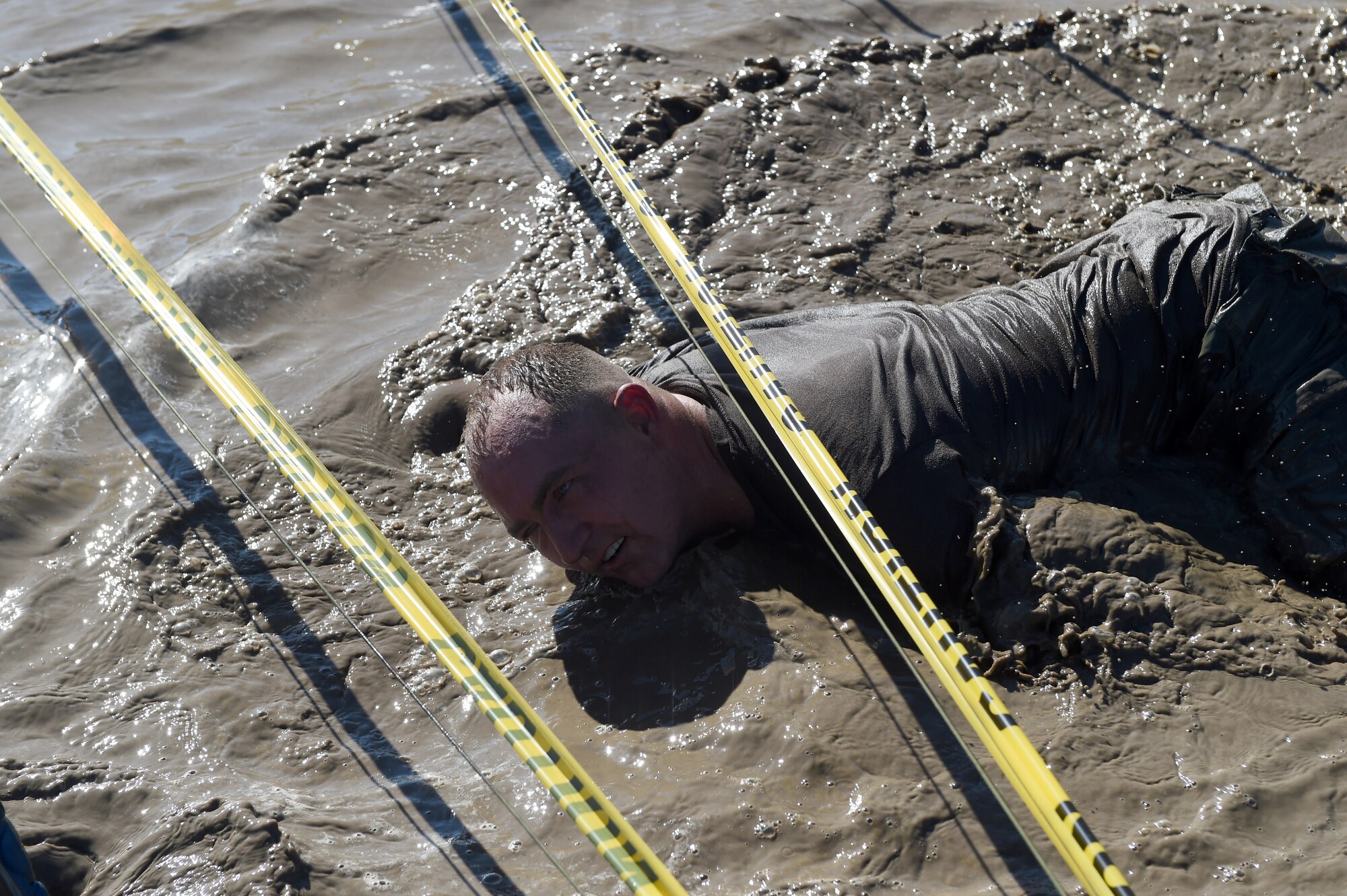 Senior Master Sgt. Shane Enos traverses the low-crawl obstacle during WARFIT Sept. 25, 2014, on Buckley Air Force Base, Colo. The 460th Civil Engineer Squadron hosted the September WARFIT, which consisted of a 5K run and a mud obstacle course. WARFIT is a way for the 460th Space Wing and base partner units to get together and stay physically fit. (U.S. Air Force photo by Airman Emily E. Amyotte/Released)