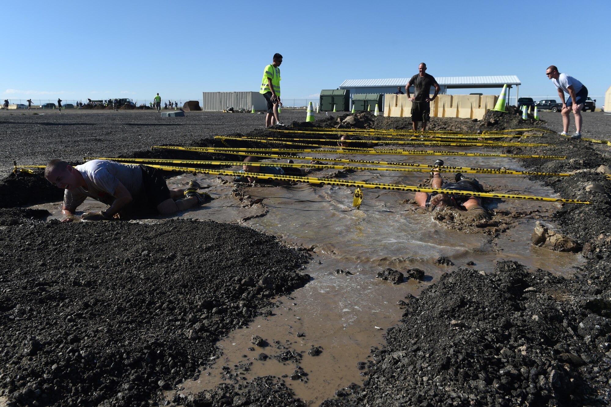 Team Buckley members traverse the low-crawl obstacle during WARFIT Sept. 25, 2014, on Buckley Air Force Base, Colo. The 460th Civil Engineer Squadron hosted the September WARFIT, which consisted of a 5K run and a mud obstacle course. WARFIT is a way for the 460th Space Wing and base partner units to get together and stay physically fit. (U.S. Air Force photo by Airman Emily E. Amyotte/Released)