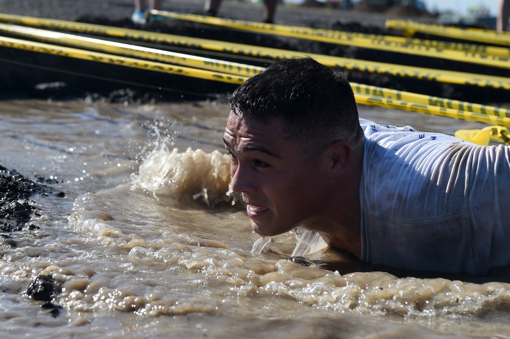 A Team Buckley member pushes through the low-crawl obstacle during WARFIT Sept. 25, 2014, on Buckley Air Force Base, Colo. The 460th Civil Engineer Squadron hosted the September WARFIT, which consisted of a 5K run and a mud obstacle course. WARFIT is a way for the 460th Space Wing and base partner units to get together and stay physically fit. (U.S. Air Force photo by Airman Emily E. Amyotte/Released)