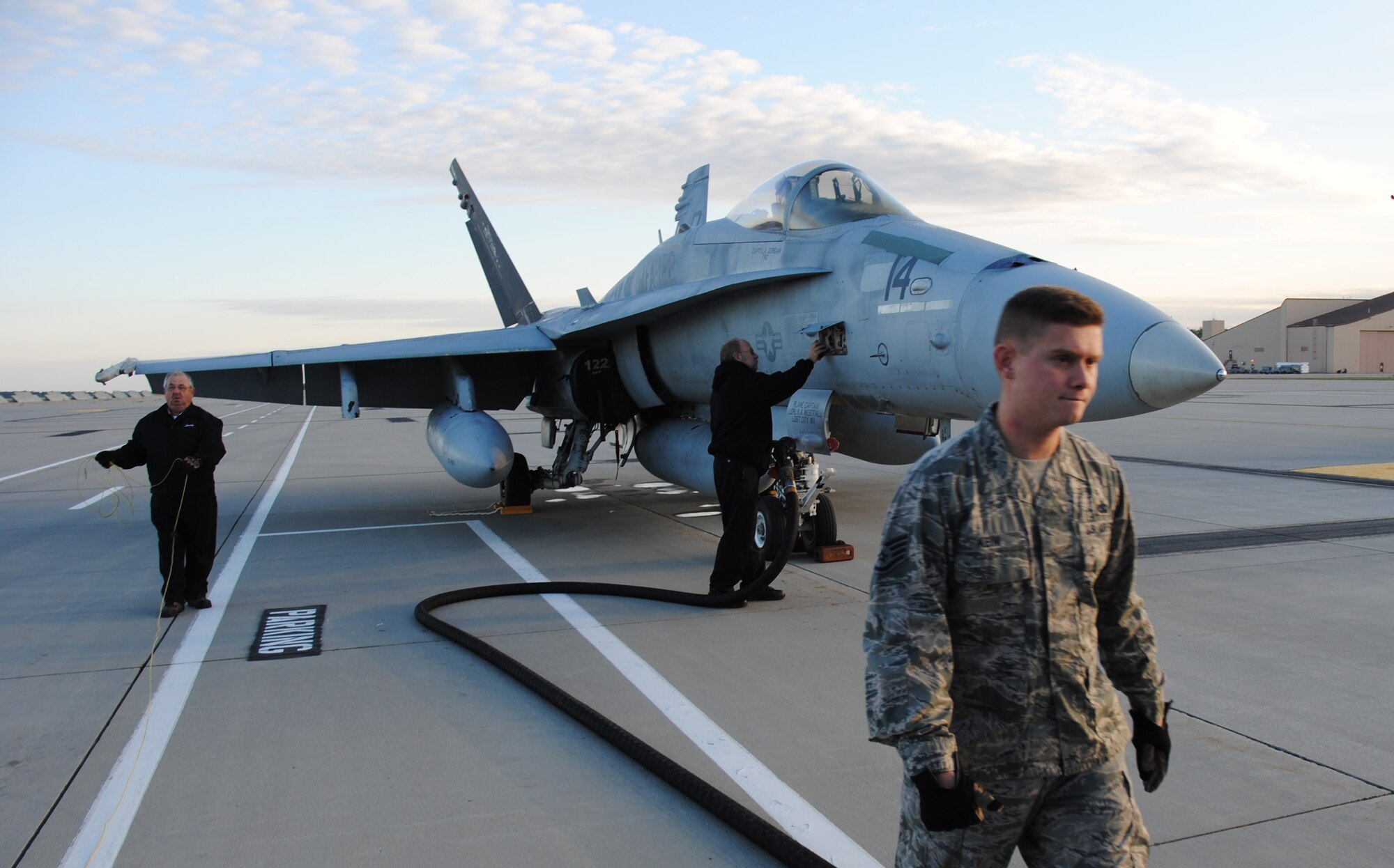 (Right) Staff Sgt. Titus Kiem, 319th Logistics Readiness Squadron water and fuels expediter, along with Transient Alert Air Craft servicer John Winter and Transient Alert Air Craft project manager Larry Crouch prepare to refuel one of three F-18 Hornets from Marine Fighter Attack Squadron 122 on Sept.  16, 2014, at Grand Forks Air Force Base, N.D. Nearly a dozen of Marine Corps pilots and aircraft made pit stops at Grand Forks AFB in order to rest and refuel while on their way to their home station of Marine Corps Air Station Beaufort, S.C. Marine Corps aircraft are a rare site at Grand Forks AFB. The base’s zero manned aircraft operations allows the base to serve as safe haven for aircraft during severe weather in other parts of the country, such as aircraft that were evacuated from the east coast during Super Storm Sandy. This also allows the base to serve as a refueling and resting point for aircraft and crews traveling across the country. (U.S. Air Force photo/Staff Sgt. Luis Loza Gutierrez) 