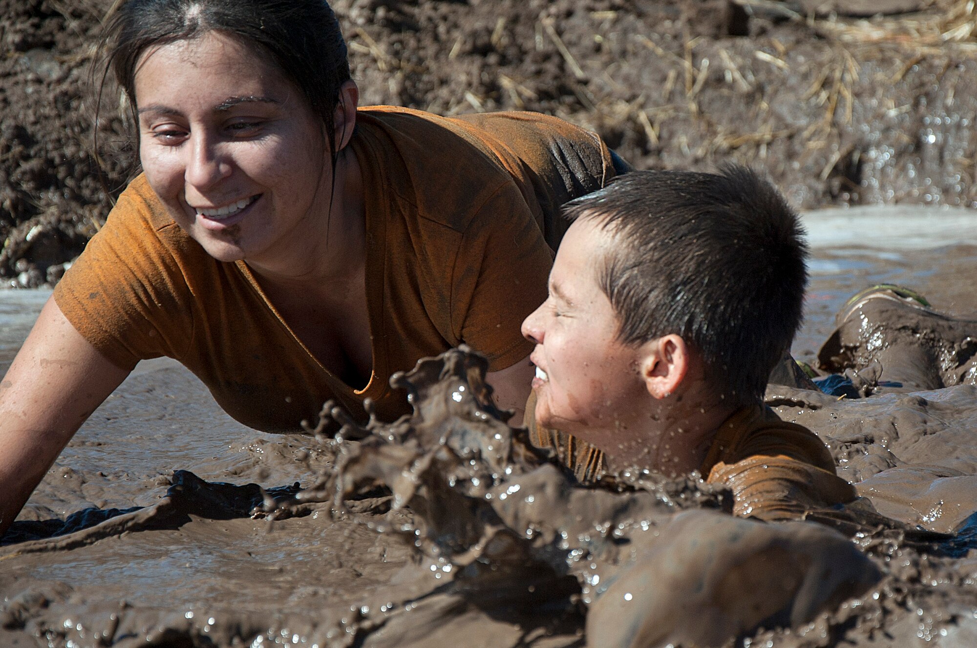 Gabriela Erdman, wife of Staff Sgt. Adam Erdman, 37th Helicopter Squadron, and her son Daniel, 9,wade through mud during the Warren Top 3 Mud Run Sept. 27. The run attracted over 100 Airmen and their families. (U.S. Air Force photo by Airman 1st Class Brandon Valle)