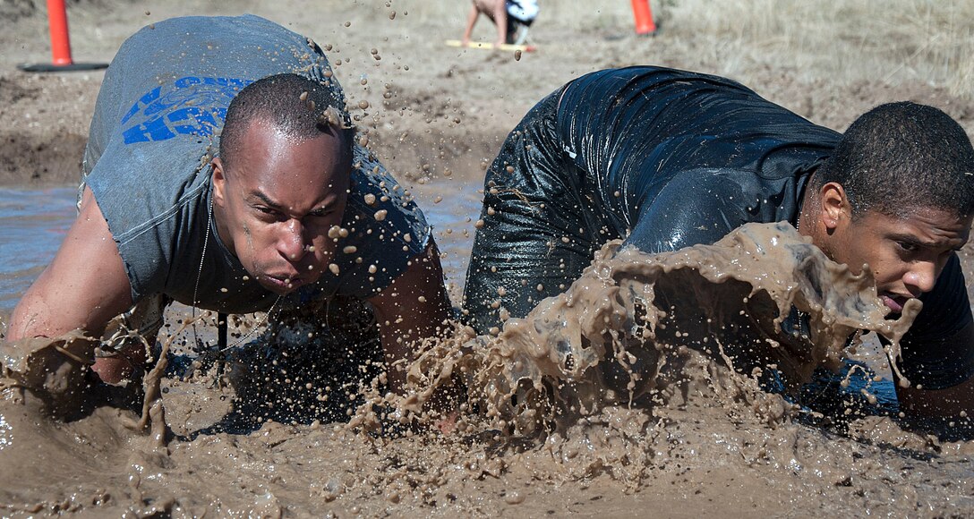 Senior Airman Jaquell Walker, 90th Missile Security Forces Squadron, and Airman 1st Class Andy Vargas, 790th Missile Security Forces Squadron, crawl through muddy water during the Warren Top 3 Mud Run Sept. 27. Walker and Vargas competed on a team that finished in third place.  (U.S. Air Force photo by Airman 1st Class Brandon Valle)