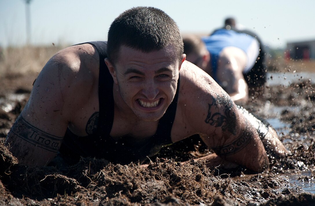 Staff Sgt. Zachary Davidson, 90th Civil Engineer Squadron, performs a 25-meter low crawl through fresh mud Sept. 27 while competing in the Warren Top 3 Mud Run. Airmen and their families came out to the 90th CES Training Yard to compete in the run. (U.S. Air Force photo by Airman 1st Class Brandon Valle)
