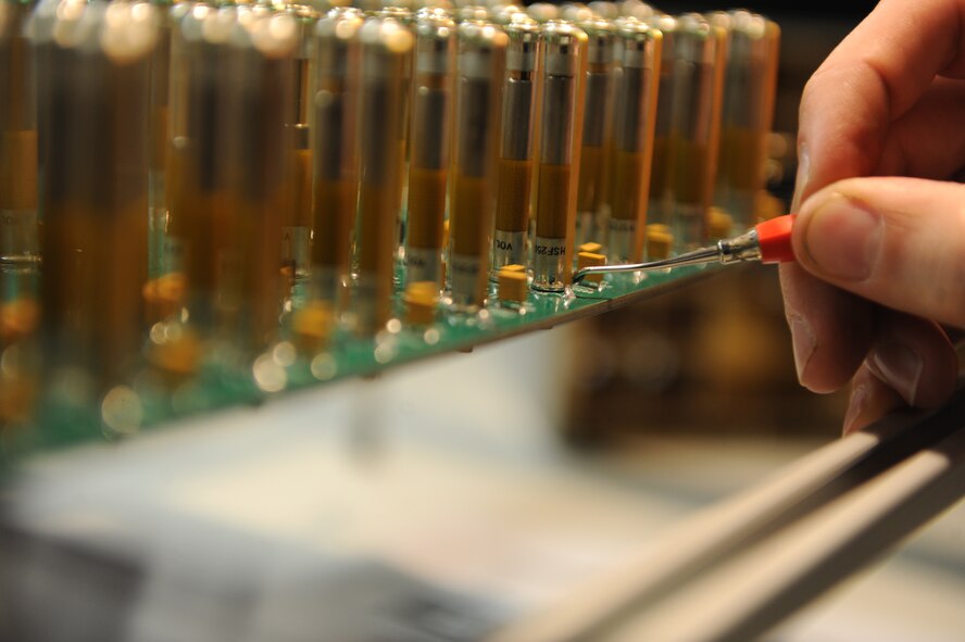 U.S. Air Force Tech. Sgt. Tyler Atkins, 7th Maintenance Group Air Force Repair/Enhancement Program (AFREP) manager, inspects capacitors on a circuit card assembly Aug. 28, 2014, at Dyess Air Force Base, Texas. The AFREP shop is responsible for repairing especially-costly pieces of equipment or equipment essential to the mission. (U.S. Air Force photo by Airman 1st Class Alexander Guerrero/Released)