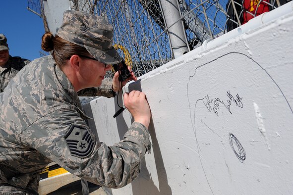 Master Sgt. Breah Misho, 436th Operations Support Squadron first sergeant, signs the wall near the starting line of the Monster Mile prior to the NASCAR Nationwide Series Race Sept. 27, 2014 at the Dover International Speedway in Dover, Del. Misho served as an honorary pit crew member for Blake Koch, driver of the no. 10 car, and was able to spend time with his pit crew and watch the race from his pit box. (U.S. Air Force photo/Staff Sgt. Elizabeth Morris)