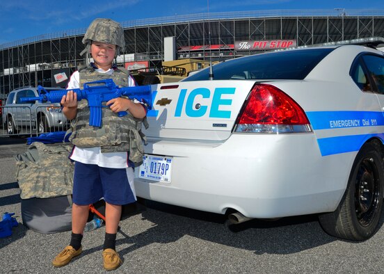 NASCAR fan Cooper Johnson poses in full battle-rattle and with a M-4 trainer rifle in front of a 436th Security Forces Squadron vehicle Sept. 28, 2014, in the Fan Zone on Dover International Speedway in Dover, Del. The 436th SFS let fans try on battle-rattle and showed them the interior components of the squad car. (U.S. Air Force photo/Airman 1st Class William Johnson)