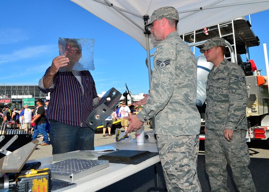 Senior Airman Jordan Heater and Airman 1st Class Adam Gauntt, 436th Maintenance Squadron aircraft structural maintenance journeymen, show NASCAR fan Robert Holt a piece honeycomb core used in the C-5 Super Galaxy Sept. 28, 2014, at The USO Village on Dover International Speedway in Dover, Del. Team Dover contributed more than 80 volunteers to The USO Village over the race weekend. (U.S. Air Force photo/Airmen 1st Class William Johnson)