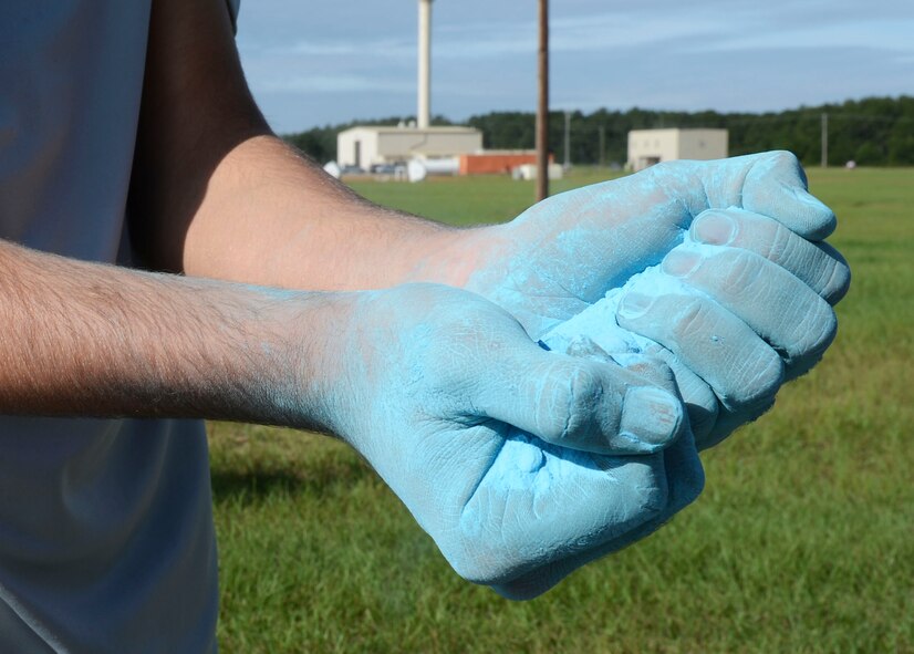 A junior ROTC volunteer from a local high school, grasps a handful of blue cornstarch powder to cover runners passing by during the Shut Up and Color Run at Shaw Air Force Base, S.C., Sept. 27, 2014. Shaw’s second annual Shut Up and Color Run 5K, runners were covered in five different colors as they participated in the event. (U.S. Air Force photo by Senior Airman Tabatha Zarrella/Released)