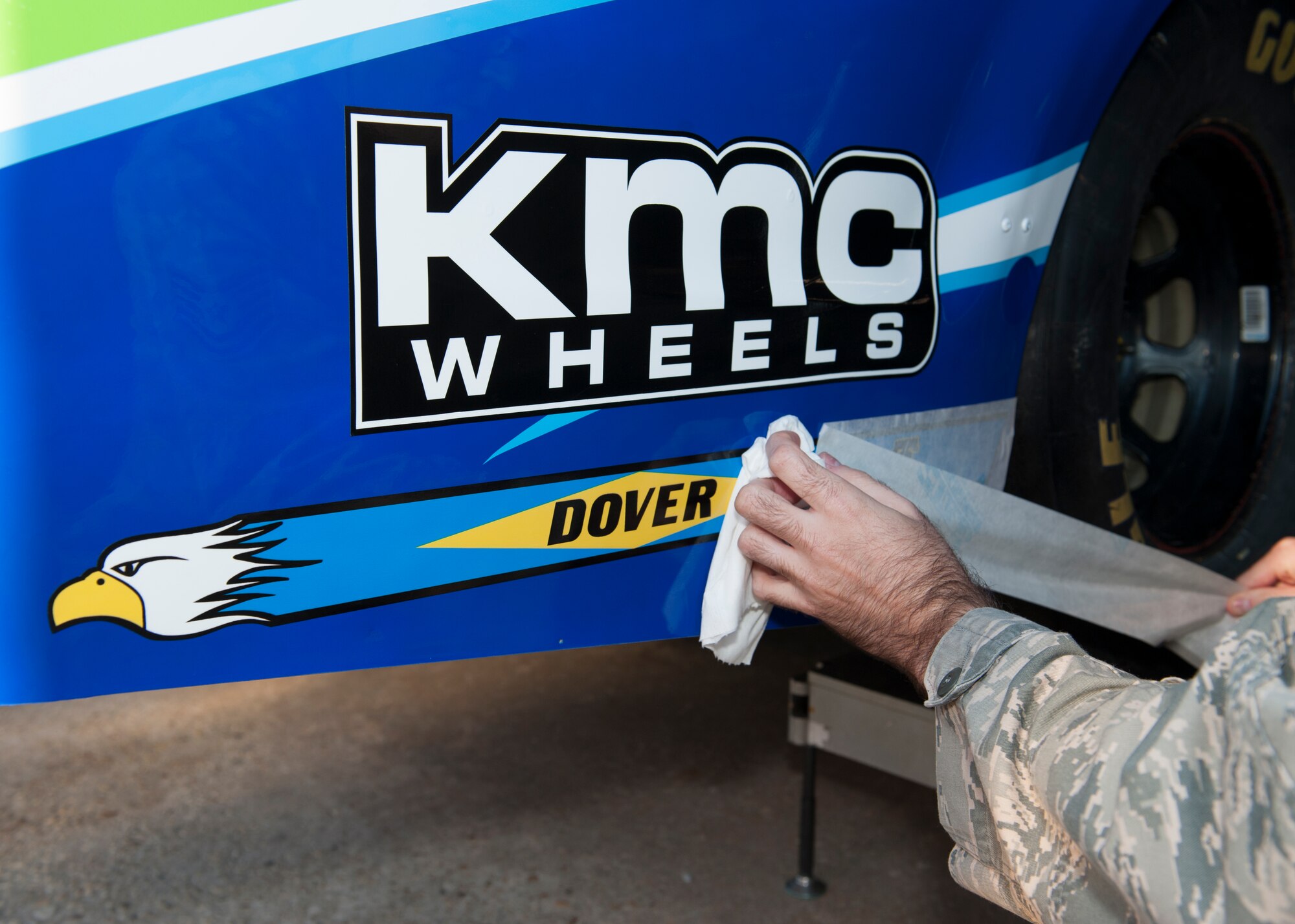 Tech. Sgt. Duncan Alexander, 436th Maintenance Squadron aircraft structural maintenance, applies a Dover tailflash decal to the Germain Racing #13 GEICO Chevy SS Sept. 26, 2014, at Dover International Speedway in Dover, Del. Duncan and two other maintainers were invited to the team’s garage to place tailflashes on the car. (U.S. Air Force photo/Airman 1st Class Zachary Cacicia) 