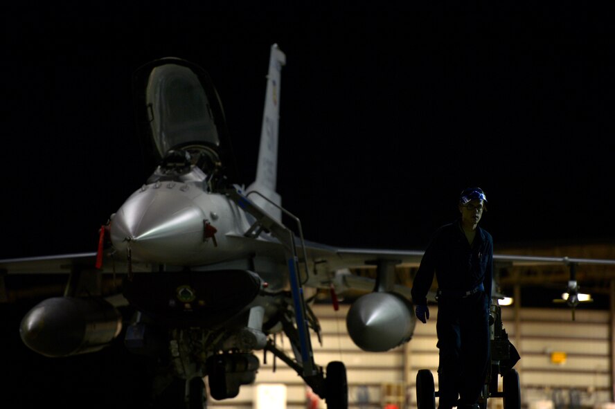 A U.S. Air Force crew chief transports his gear from one aircraft to the next during night flying operations at Shaw Air Force Base, S.C., Sept. 18, 2014. Each dedicated crew chief is assigned to an F-16 and works around the clock to maintain the aircraft keeping the war plane mission capable. (U.S. Air Force photo by Staff Sgt. Kenny Holston/Released)