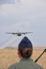 MOUNTAIN HOME AIR FORCE BASE, Idaho – Air Force Reserve Maj. Jen Remmers, an entomologist assigned to the 910th Airlift Wing’s 757th Airlift Squadron, watches as a C-130 Hercules aircraft, assigned to the 910th Airlift Wing, flies toward her position on the ground at nearby Saylor Creek Bombing Range here, Sept. 17, 2014, spraying herbicide to control the cheat grass in the area. The wing, based at Youngstown Air Reserve Station, Ohio, is home to the Department of Defense’s only large-area, fixed-wing aerial spray capability, conducted a mission to spray herbicide on invasive cheat grass as a means of fire prevention here, Sept. 15-26, 2014. U.S. Air Force photo by Master Sgt. Bob Barko Jr.
