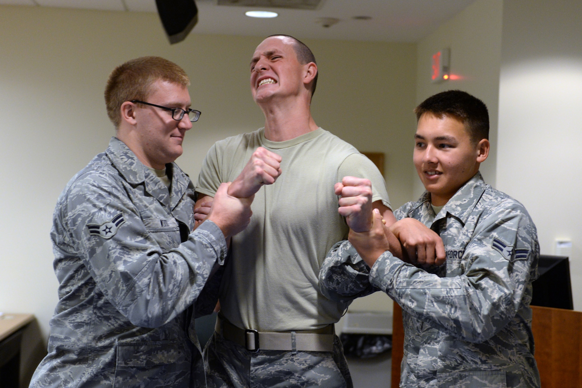Airman 1st Class Seth Tomb (center), 375th Communications Squadron, cringes while being tased during a 375th Security Forces Squadron augmentee training session Sept. 25, 2014 at Scott Air Force Base, Ill. Tomb volunteered to be tased to demonstrate the effects to his fellow classmates. (U.S. Air Force photo/Staff Sgt. Jonathan Fowler)