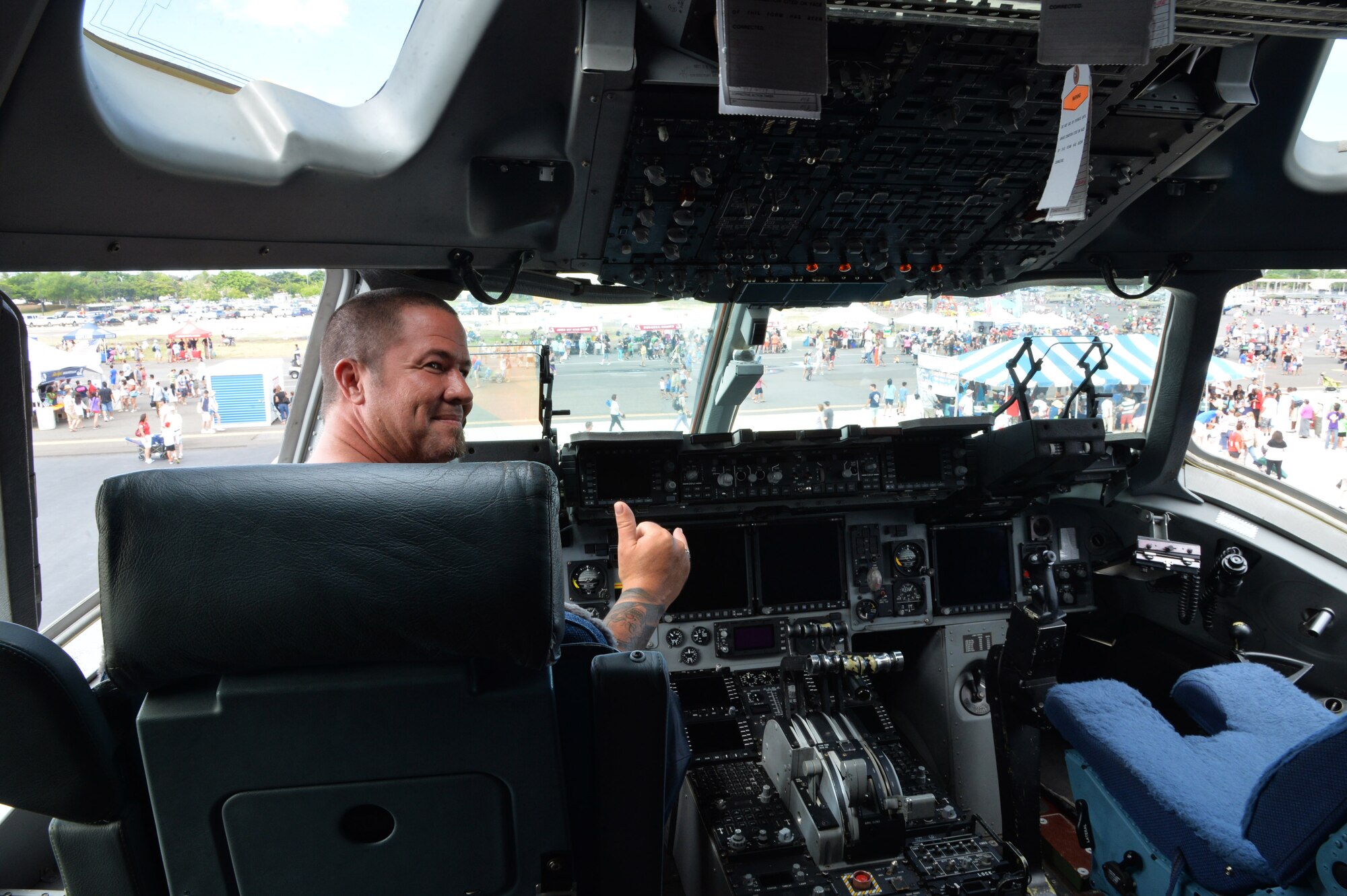An attendee sits in the pilot chair of a C-17 Globemaster III and throws up a "shaka" at the Wings Over the Pacific Air Show, Joint Base Pearl Harbor-Hickam, Hawaii, Sept. 27, 2014. Inside the aircraft, air crew members were present to answer any questions. Thousands of spectators witnessed aerial performances by demonstration teams including the F-22 Raptor Aerial Demonstration Team and the Navy Blue Angels. (U.S. Air Force photo by Staff Sgt. Alexander Martinez/Released)  