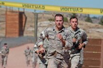 Senior Airman Patrick Wagenecht and Senior Airman Cody Poole, 91st Security Forces Group Global Strike Challenge team members, run to the finish line during the mental and physical challenge on Camp Guernsey Wyo., Sept. 25, 2014. Nine teams competed in the security forces portion of the challenge. (U.S. Air Force photo/Senior Airman Brittany Y. Bateman)