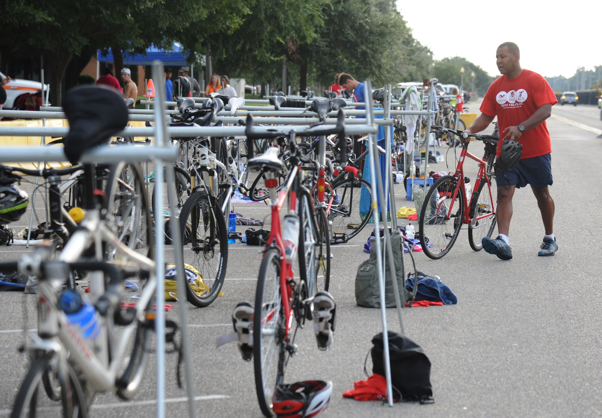 Master Sgt. Chris Richards, 338th Training Squadron, walks his bike to the racks as he transitions from cycling to running during Keesler's mini-triathlon Sept. 26, 2014, at Keesler Air Force Base, Miss.  The event included a 9-mile bike ride, a 2-mile run and a 200-yard swim.  (U.S. Air Force photo by Kemberly Groue)