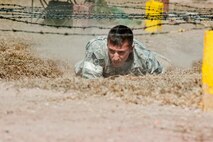 Senior Airman Cody Poole, 91st Security Forces Group Global Strike Challenge team member, low crawls through an obstacle during the mental and physical challenge on Camp Guernsey Wyo., Sept. 25, 2014. The security forces portion of the challenge was split into three different events; tactics, weapons firing, and the mental and physical challenge. (U.S. Air Force photo/Senior Airman Brittany Y. Bateman)