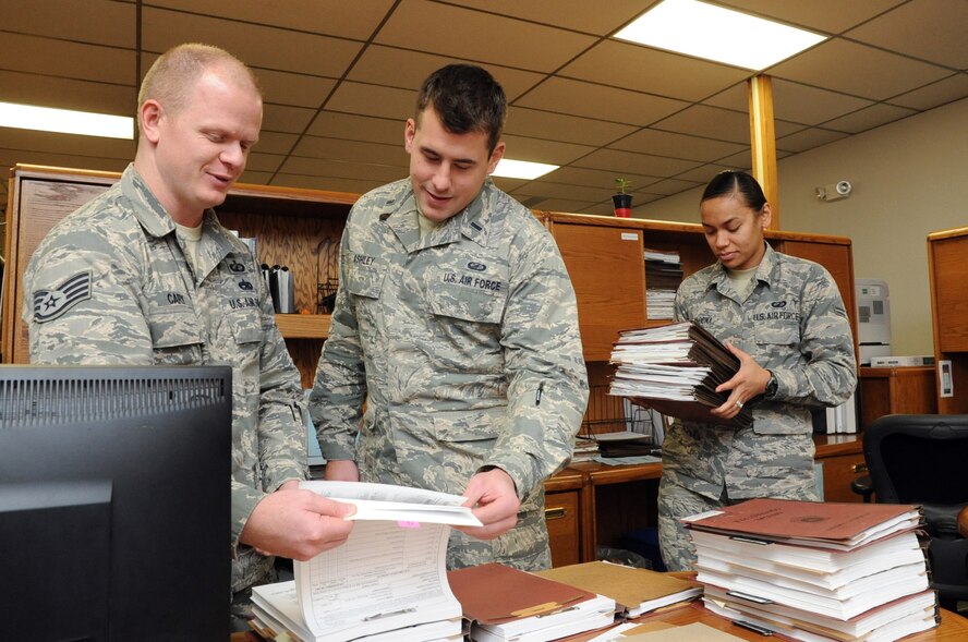 Staff Sgt. Daniel Cary, 1st Lt. Aaron Ashley and Senior Airman Irinieta Tabuyaqona, 319th Contracting Flight contract specialists, pore over various support agreements in the 319th CONF office on Grand Forks Air Force Base, N.D., Sept. 25, 2014. The 319th CONF creates and oversees contracts ranging from small purchases of supplies to multimillion dollar construction projects. (U.S. Air Force photo/Staff Sgt. David Dobrydney)