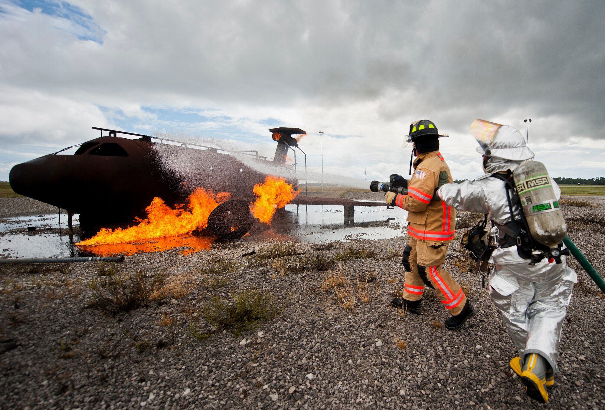 Brig. Gen. David Harris, 96th Test Wing commander, attacks the aircraft fire with the help of base firefighter, Senior Airman Micah Moody, Sept. 29 at Eglin Air Force Base, Fla.  Harris visited the 96th TW flightline fire department and participated in hands-on firefighter training including live fire, structural and confined spaces.  (U.S. Air Force photo/Samuel King Jr.)