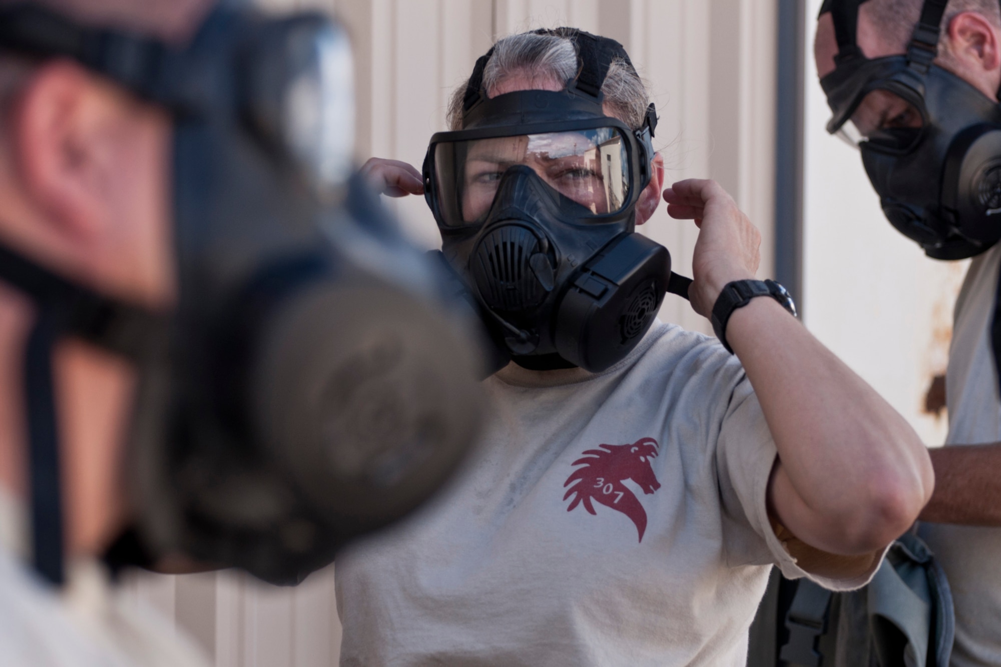 U.S. Air Force Master Sgt. Jessica Wiley, NCOIC of vehicle maintenance, 307th RED HORSE Squadron, dons a M50 Joint Service General Purpose Field Mask at Barksdale Air Force Base, La., Sept. 10, 2014. The Airmen were practicing operations in a contaminated environment using the masks, which is a yearly requirement for field skills training. (U.S. Air Force photo by Master Sgt. Jeff Walston/Released)