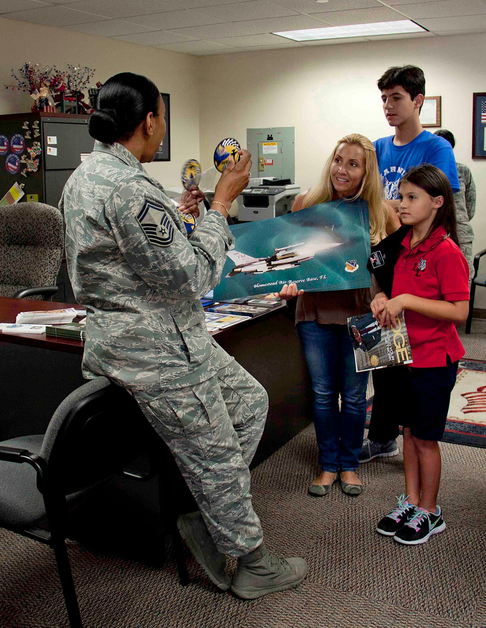 Senior Master Sgt. Wanda Symons, Military Personnel Programs chief for the 482nd Force Support Squadron at Homestead Air Reserve Base, Fla., presents students from the Learning Links School in Miami, Fla., with unit patches, F-16 posters, and Air Force Reserve sunglasses during their visit to the Airman and Family Readiness office at Homestead ARB Sept. 19. Service members greeted the students, when they visited to donate an assortment of food, snacks, games, and toiletries to send to our troops serving overseas. The Learning Links School caters to students with special needs. (U.S. Air Force photo/Senior Airman Aja Heiden)