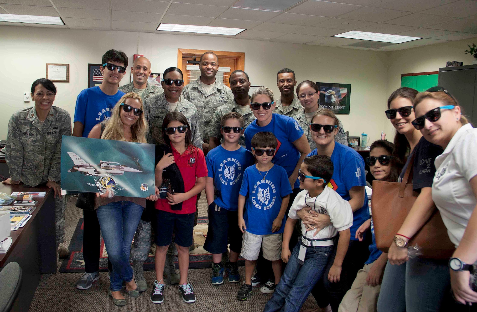 Service members from Homestead Air Reserve Base, Fla., and students from Learning Links School in Miami, Fla. pose together for a final photo before departing the Airman and Family Readiness office at Homestead ARB. Sept. 19. The Learning Links School, which caters to students with special needs, visited to donate an assortment of food, snacks, games, and toiletries to our troops serving overseas. (U.S. Air Force photo/Senior Airman Aja Heiden)