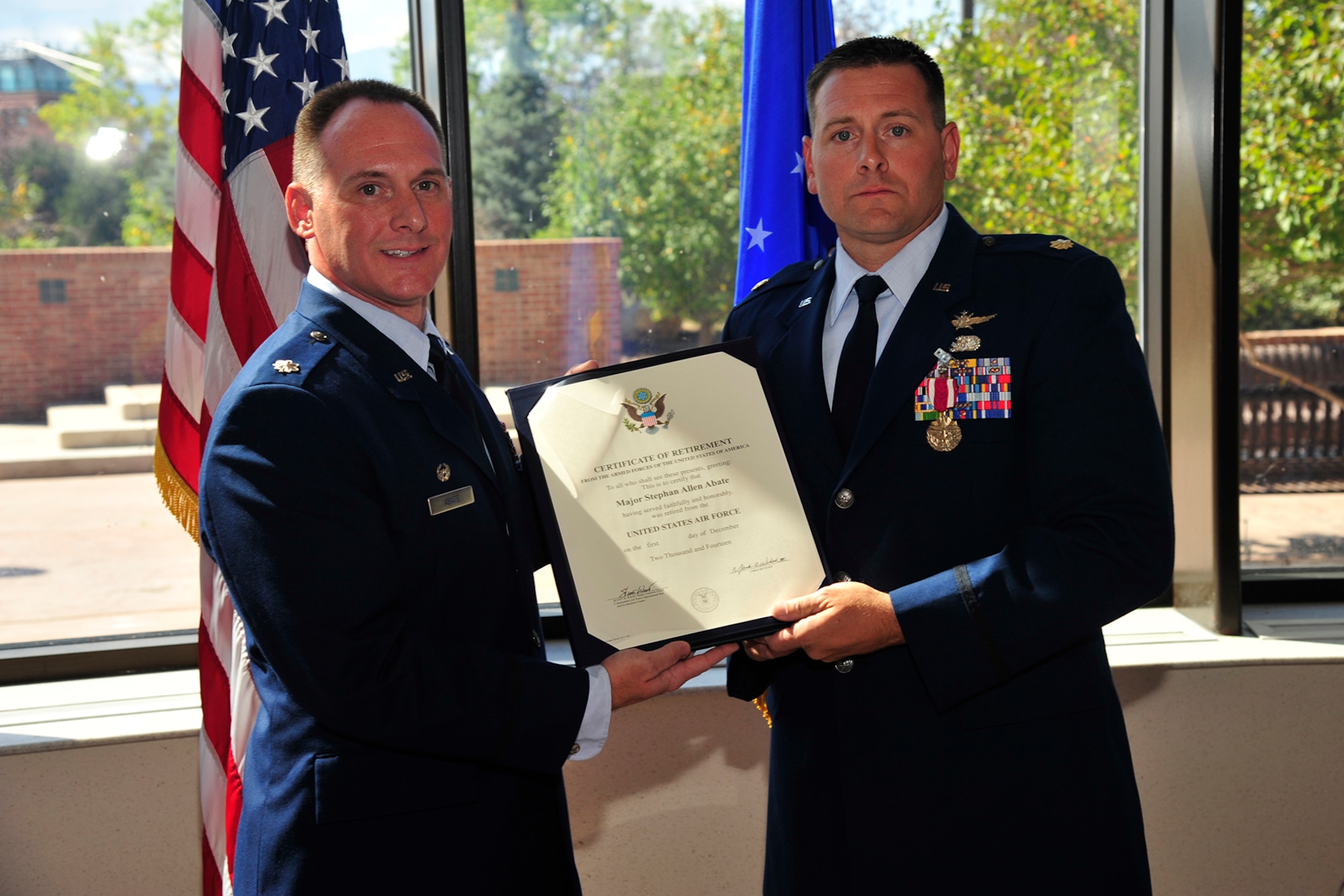 PETERSON AIR FORCE BASE, Colo. —Lt. Col. Christopher Abate (left), 21st Comptroller Squadron commander presents his younger brother, Maj. Stephan Abate, Operational Test and Evaluation Center Detachment 4 test director, with his Certificate of Retirement during a ceremony attended by family, friends and longtime coworkers. (U.S. Air Force photo/Robb Lingley)
