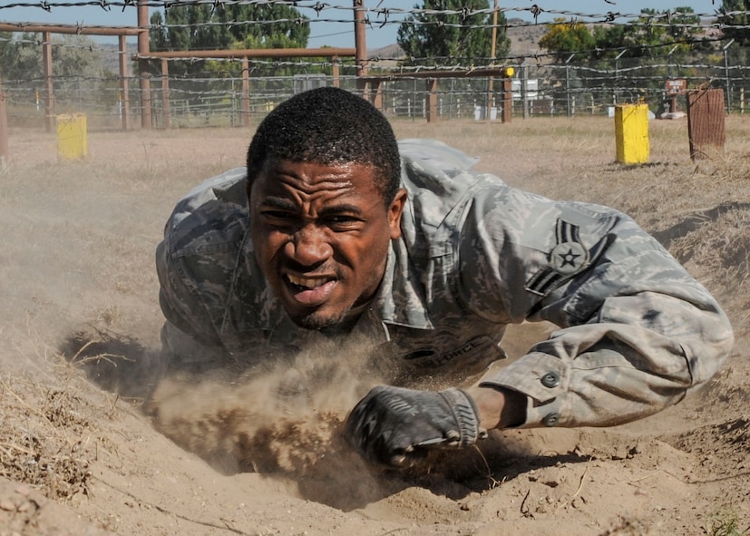 Airman 1st Class Michael Clayton, 5th Security Forces Squadron Global Strike Challenge team member, crawls under barbed wire during the obstacle course portion of the competition at Camp Guernsey, Wyo., Sept. 25, 2014. The obstacle course was the final event of the three-day competition, which also included tactics and shooting evaluations. (U.S. Air Force photo/Senior Airman Stephanie Morris)