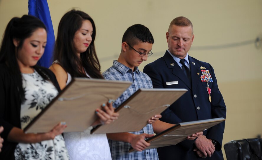 U.S. Air Force Chief Master Sgt. Michael Goetz, 93d Air Ground Operations Wing command chief, looks on as his children (from left) Sharon, Nicole and Michael, read the citation for a children’s medal he presented to them during his retirement ceremony Sept 26, 2014, at Moody Air Force Base, Ga. Following his retirement, Goetz will join his family in Panama City, Fla. (U.S. Air Force photo by Andrea Jenkins/Released)