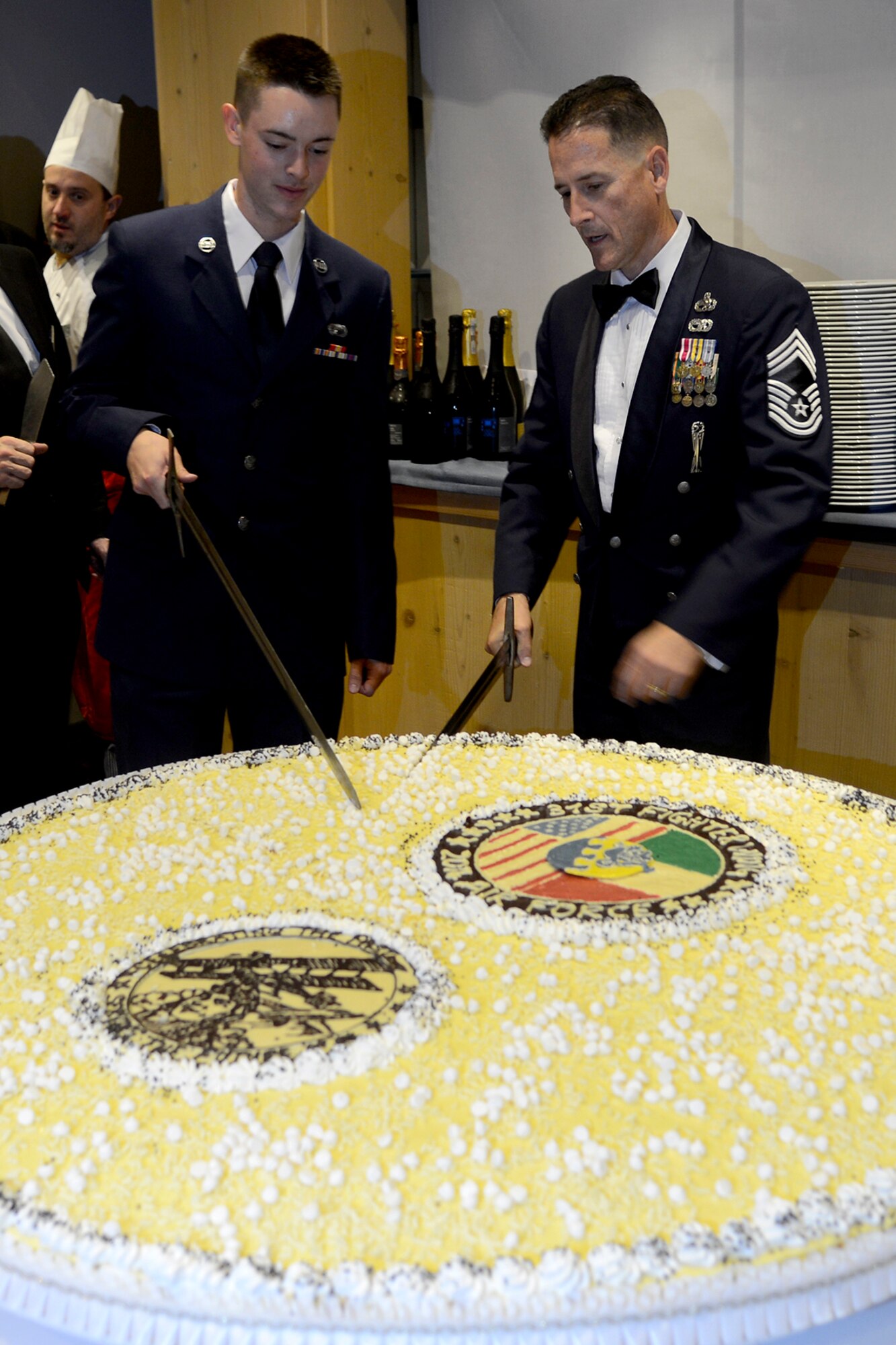 Chief Master Sgt. Steven Bowersox, 31st Munitions Squadron and Airman Basic Justin Meochnig, 31st Contracting Squadron, cut the birthday cake at the Aviano Air Force Ball, Sept. 26, 2014, at Castel Brando. This time-honored tradition symbolizes the wisdom of the older service member being passed down to the new generation of Airmen.  (U.S. Air Force photo/Staff Sgt. Jessica Hines)