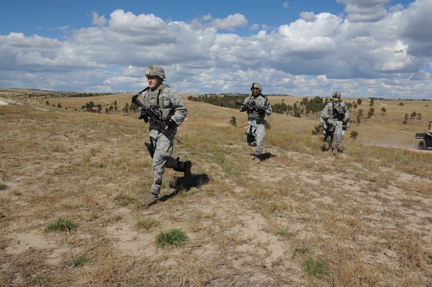 Members of the 5th Security Forces Squadron Global Strike Challenge team run to their positions during the shooting portion of the competition at Camp Guernsey, Wyo., Sept. 23, 2014. Between firing weapons, the team had to run up steep inclines and rode from site to site in the back of an Army transport vehicle. (U.S. Air Force photo/Senior Airman Stephanie Morris