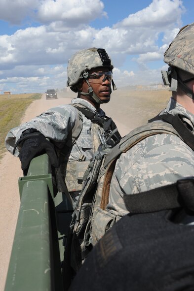 Airman 1st Class Michael Clayton, 5th Security Forces Squadron Global Strike Challenge team member, rides in the back of a truck during the shooting portion of the competition at Camp Guernsey, Wyo., Sept. 23, 2014. Between firing weapons, the team ran up steep inclines and rode from site to site in the back of an Army transport vehicle. (U.S. Air Force photo/Senior Airman Stephanie Morris)