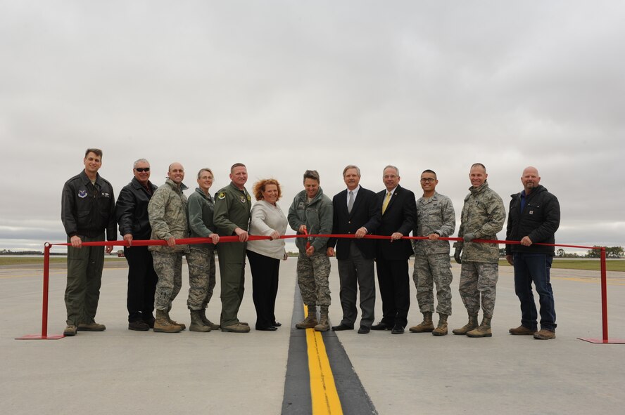 Base and community leaders join Col. Jason Armagost, 5th Bomb Wing commander, as he cuts a ribbon during a ceremony to commemorate the completion of the new runway on Minot Air Force Base, N.D., Sept. 29, 2014. The project began in early April and cost approximately $57 million to complete. The recent construction marks the first replacement of the flightline. (U.S. Air Force photo/Senior Airman Stephanie Morris)
